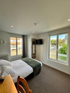 a bedroom with a bed and a large window at Le Clos Normand in Saint-Aubin-sur-Mer