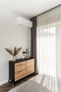 a bedroom with a bed and a dresser with a window at Riverra House - Panorama View Apartment in Kaunas