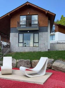 dos sillas blancas sentadas frente a una casa en Mount Inn Villa, en Bakuriani