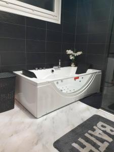 a white bath tub in a bathroom with black tiles at Maison cosy au calme avec jardin in Agen
