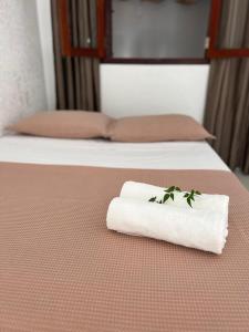 a white towel with a plant on a bed at Milagres de Minas in São Miguel dos Milagres