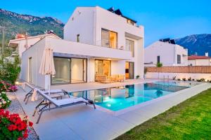 费特希耶Villa İon İndoor heated pool, Sauna, Jacuzzi, Underfloor heating system的一栋房子前面有游泳池的别墅