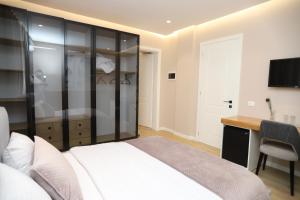 J&D Rooms Korce في كورتشي: غرفة نوم بسرير ومكتب وتلفزيون