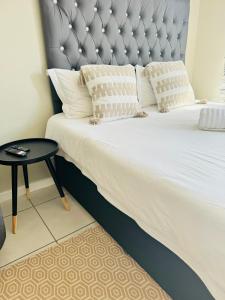 a large bed with a gray headboard and a table at Gallagher Midrand BnB in Midrand
