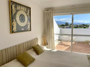 1 dormitorio con cama y ventana grande en Duplex vistas al golf Guadalmina Marbella, en Marbella