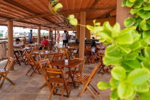 an empty restaurant with wooden tables and chairs at Pousada Rota do Kite Preá in Prea