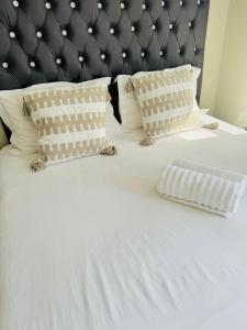 Gallagher Midrand BnB في ميدراند: سرير أبيض مع وسادتين و اللوح الأمامي أسود