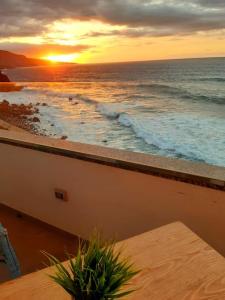 a sunset over the ocean with a table on a balcony at Ocean Orchidea in Puerto de la Cruz