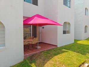 a pink umbrella over a table on a patio at Paraíso Teques, Casa entera con acceso al lago in Tequesquitengo