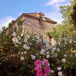 uma casa de pedra com flores em frente em LA MAISON FORTE em Montaut
