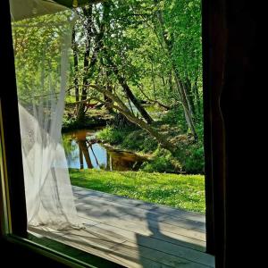 d'une fenêtre offrant une vue sur la rivière depuis une maison. dans l'établissement River House, à Nītaure