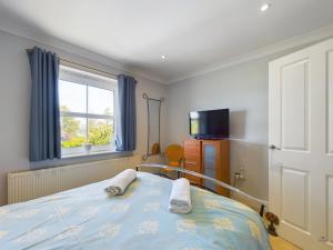 a bedroom with a bed and a television and a window at 12A Solent Landing direct beach access in Bembridge