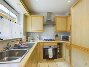 a kitchen with wooden cabinets and a sink and a stove at 12A Solent Landing direct beach access in Bembridge