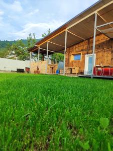 a barn with a grass field in front of it at NORDIC уютный домик в скандинавском стиле в горах Алматы in Besqaynar