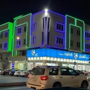 une voiture blanche garée devant un bâtiment la nuit dans l'établissement ريحانة حى الخبر للشقق الفندقيه, à Khobar