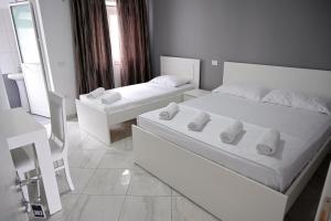 a white bedroom with two beds and a mirror at Hotel 'DEL MAR' - Shengjin in Shëngjin
