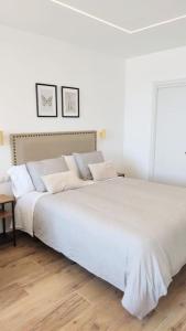 Un dormitorio con una gran cama blanca con dos cuadros en la pared. en 24 h Self Check-in Vistas al Mar, en Torremolinos