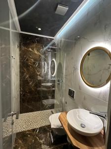 a bathroom with a sink and a shower with a mirror at Hotel Utopia in Ksamil