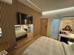 a hotel room with a bed and a tv on a wall at Mirada Hotel in Athens