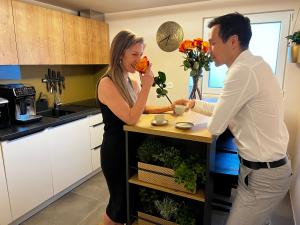 a man and a woman standing in a kitchen at JUNGLE Wellness Apartment in Trzin