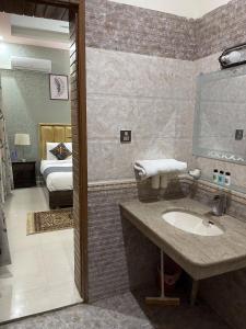 uma casa de banho com um lavatório e um quarto com uma cama em Safari Hotel em Islamabad