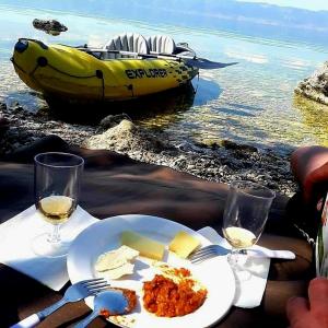 a table with a plate of food and two glasses of wine at VN APARTMENTS OHRID in Ohrid