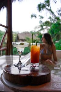 プエルト・ミサウアリにあるSuchipakari Amazon Eco -Lodge & Jungle Reserveの浴槽に座った女性と一緒にテーブルの上で飲み物