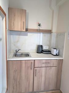 uma cozinha com armários de madeira e um lavatório em Asteri Studios em Kalamaki