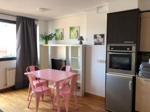 uma pequena cozinha com uma mesa rosa e cadeiras em Apartamento El Ático de Celorio em Celorio