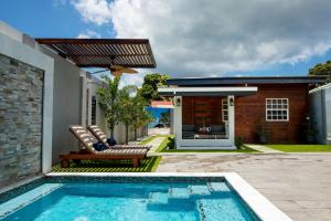 a swimming pool in front of a house at Jazuri Villa in Buccoo