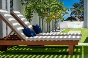 a bench with blue pillows sitting on the grass at Jazuri Villa in Buccoo