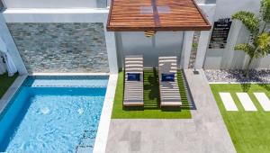 a house with a swimming pool with a deck and a house at Jazuri Villa in Buccoo +18 photos