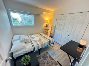 a small bedroom with a bed and a table at Modern Cozy Home W Free Parking- Close to Downtown & Beach in Victoria