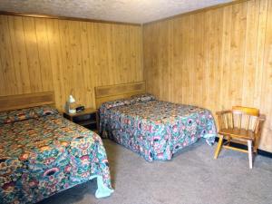 una habitación de hotel con 2 camas y una silla en Davis Motel, en North Lima