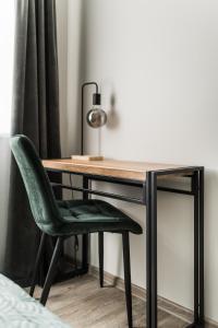 a desk with a green chair and a lamp at Riverra House in Kaunas