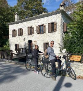 a man and a woman on a bike in front of a building at Archontiko Michael Pelion in Vyzitsa
