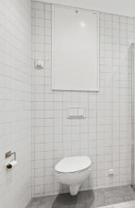 a white tiled bathroom with a toilet and a mirror at 7,3sq mts room -Forests cozy house in Stavanger