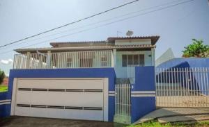 une maison bleue et blanche avec un garage dans l'établissement Chácara Aloés - suíte com ar cond banheira hidromassagem, à Socorro