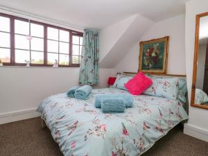 um quarto com uma cama com almofadas azuis e cor-de-rosa em Rhodale Cottage em Barmston