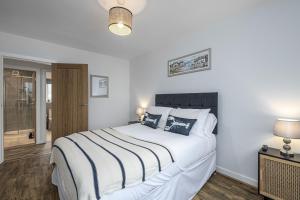 a bedroom with a large white bed with two lamps at Cenarth in Benllech