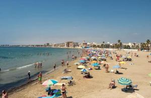 eine Menschenmenge an einem Strand mit Sonnenschirmen in der Unterkunft BIG PENTHOUSE FOR 10 per in Torrevieja