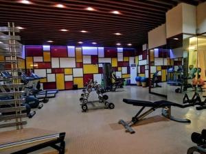 einen Fitnessraum mit mehreren Geräten und einer farbenfrohen Wand in der Unterkunft CP19P TWINBED COZY ROOM Near at Venice Mall in Manila