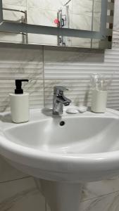 a bathroom sink with a faucet and two cups on it at Карпати Кайзервальд апарт in Karpaty