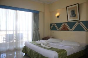 um quarto com uma cama grande e uma janela grande em New Siesta M Hotel em El Alamein