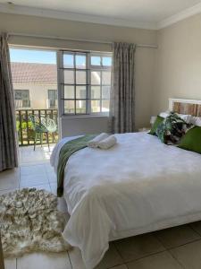 a bedroom with a large white bed and a balcony at Arabella By The Sea in Port Alfred