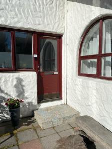 une porte rouge d'un bâtiment blanc avec un banc dans l'établissement Stay Iceland apartments - S 24, à Garðabær