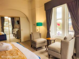 パースにあるThe Lovat Hotelのベッドと椅子、窓が備わるホテルルームです。