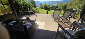 een patio met stoelen en een tafel en uitzicht op een veld bij un ptit chalet in Les Brenets