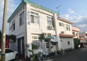 ein weißes Gebäude mit einem davor geparkt in der Unterkunft Guest House Minatoya Tokunoshima - Vacation STAY 01040v in Tokunoshima