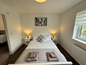 a bedroom with a bed with two nightstands and a window at Inchfad Apartment 2/1 in Bonhill